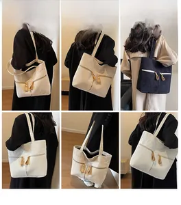 Corduroy tote bag with dual front zipper pockets shown on models in cream and black