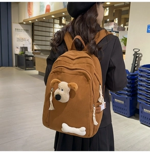 Détail du sac à dos en velours côtelé marron avec peluche de chien et décoration d'os