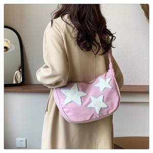 Detail view of pink nylon crescent bag with plush stars worn as a crossbody by a model