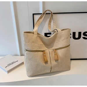 Close-up of beige corduroy tote bag featuring two front zipper pockets with leather pulls