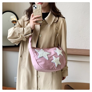 Pink nylon crescent crossbody bag with white plush star patches worn by model