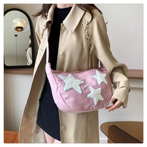 Pink nylon crossbody bag with plush star patches shown in a lifestyle model shot