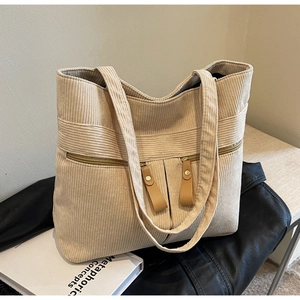 Detailed close-up of corduroy tote bag with dual front zipper pockets and leather pullers
