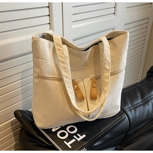 Detail of off-white corduroy tote bag with dual zipper pockets and leather pulls
