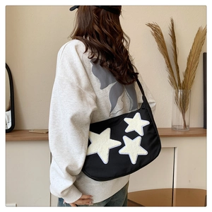 Detail of black nylon shoulder bag featuring white plush star patches on the side