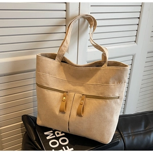 Detailed close-up of beige corduroy tote bag with vertical stripes and zipper pockets
