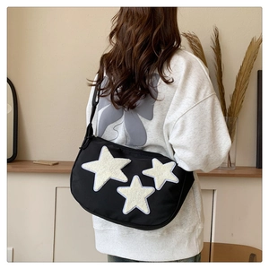Detail of black nylon crossbody bag featuring three white plush star patches on back view