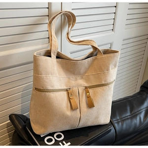 Detail view of beige corduroy tote bag featuring dual front zipper pockets and texture