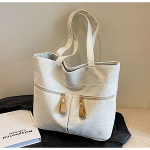 Close-up of off-white corduroy tote bag with double zipper pockets and brown leather pulls
