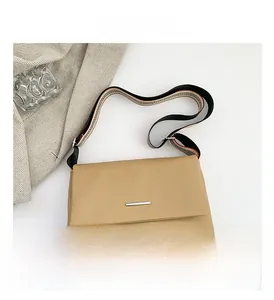 Détail montrant la texture du cuir grainé avec barre métallique et bandoulière rayée