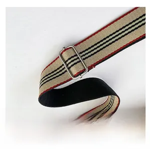Détail de la bandoulière rayée réglable avec boucle argentée sur un sac en cuir beige