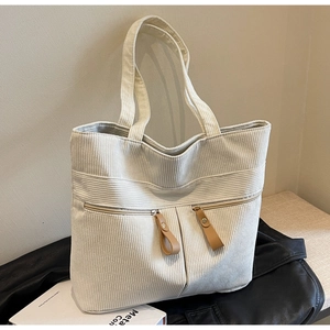 Detail of cream corduroy tote bag featuring two front zipper pockets and leather pulls