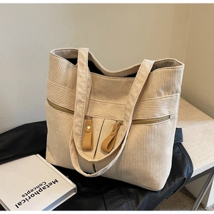 Detail of corduroy tote bag featuring vertical stripes and twin zipper pockets