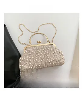 Détail d'un sac de soirée champagne élégant avec tissu plissé, perles et anneau en métal doré