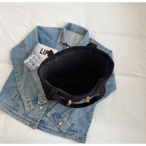 Top view of large black corduroy tote bag showing spacious interior and decorative buckle