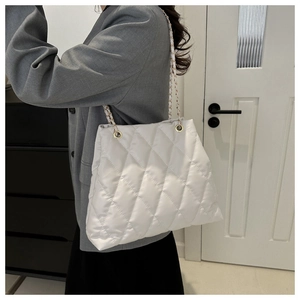 Detail van witte gewatteerde emmer tas met gouden ketting riem gedragen door een model