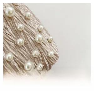 Vue détaillée du satin plissé champagne orné de perles blanches élégantes sur le sac