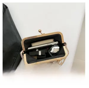 Vue intérieure montrant la capacité du sac pochette perlé avec cadre doré et maquillage