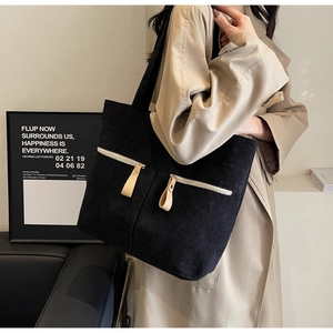 Close-up of black corduroy tote bag showing texture and dual front zipper pockets