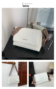 Vue détaillée du sac blanc en cuir texturé avec bandoulière rayée et boucle argentée