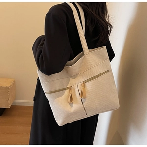 Close-up detail of cream corduroy tote bag with dual front zipper pockets and leather pulls