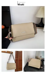 Détail du sac bandoulière en cuir grainé kaki avec sangle rayée et barre en métal argenté