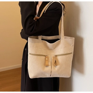 Detail view of beige corduroy tote bag showing front zipper pockets and soft texture