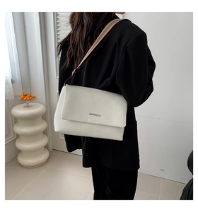 Détail du sac blanc texture litchi avec large bandoulière en tissu rayé tricolore