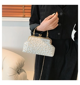 Détail du sac de soirée en perles blanches avec fermoir baiser doré et chaîne