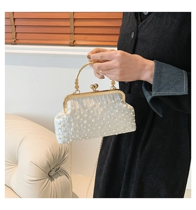 Détail du sac de soirée en satin plissé avec perles et poignée en métal doré ciselé