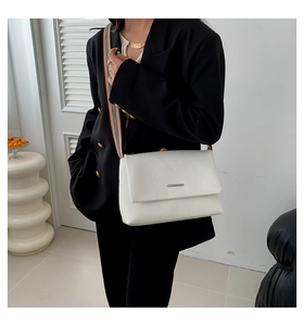 Détail du sac bandoulière blanc avec barre argentée et bandoulière en tissu rayé