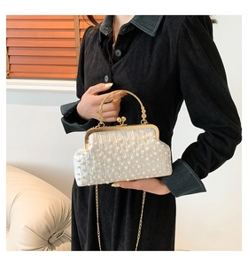 Détail du sac à bandoulière perlé avec poignée en métal doré et texture plissée
