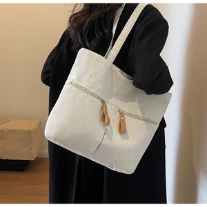 Detailed texture of beige corduroy tote bag showing side view and zipper pockets