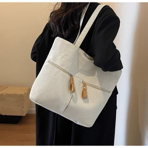 Detailed texture of white corduroy tote bag with dual zipper pockets and leather pulls