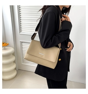 Détail du sac bandoulière crème minimaliste avec large sangle rayée sur un modèle