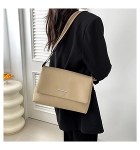 Gros plan du sac bandoulière beige en cuir grainé avec sangle en toile rayée