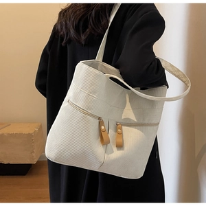 Detail of white corduroy tote bag featuring two front zipper pockets with brown leather pulls