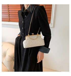 Détail de pochette en soie plissée blanche avec perles et bandoulière chaîne dorée
