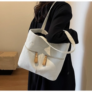 Detail of off-white corduroy tote bag showing vertical texture and dual zipper pockets