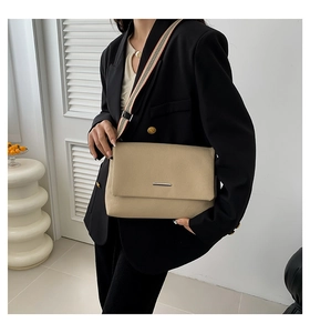 Détail du sac bandoulière en cuir kaki avec sangle rayée et boucle argentée élégante
