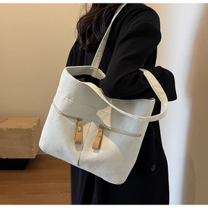 Detailed view of off-white corduroy tote bag showing vertical ribs and dual zipper pockets