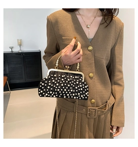 Détail d'une pochette plissée noire vintage avec perles blanches et chaîne dorée