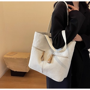 Detailed shot of cream corduroy tote bag showing dual zipper pockets and leather pulls
