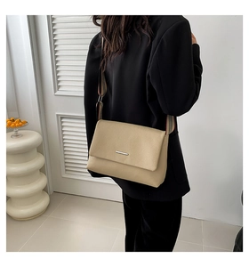 Détail d'un sac bandoulière beige avec sangle rayée large et boucle en métal argenté