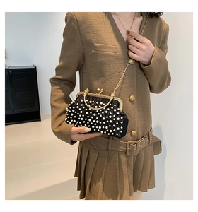 Détail d'une pochette plissée noire vintage avec décor de perles et poignée en métal doré