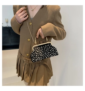 Détail d'un sac bandoulière noir élégant avec perles et fermoir doré sur modèle