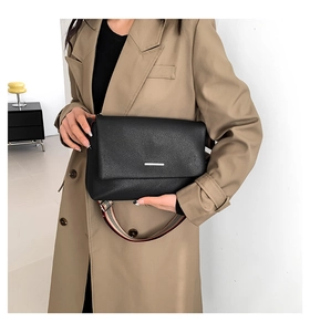 Détail du sac bandoulière en cuir noir avec bandoulière large en tissu à carreaux