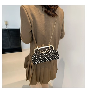 Détail du sac à main noir perlé avec poignée en métal doré et bandoulière en chaîne