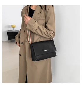 Détail du sac bandoulière en cuir noir avec sa large bandoulière à rayures colorées
