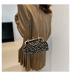 Détail d'un sac à main noir plissé avec décor de perles blanches et fermoir doré